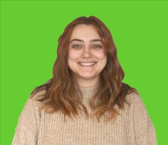 Female employee with auburn hair smiling in front of a green background