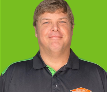 Male employee with brown hair smiling in front of a green background